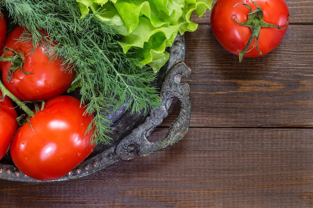 Composition from tomatoes and lettuce leaves on a wooden background. Copy Space for text.