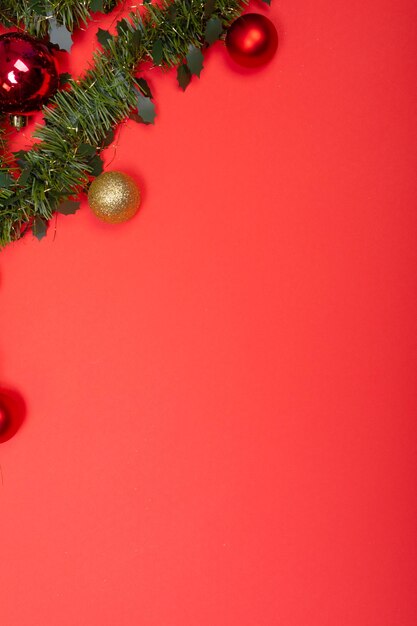 Composition of garland with baubles and copy space on red background. christmas, tradition and celebration concept