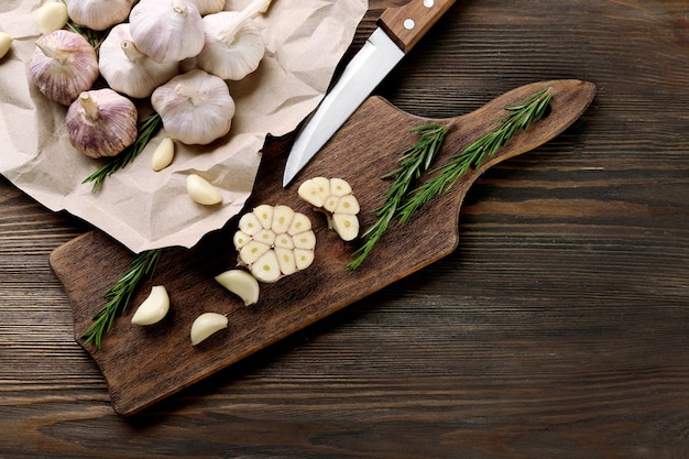 Foto composizione di aglio e rosmarino con coltello sulla tavola da cucina da vicino