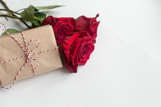 Composition of gift and bouquet of red roses on white background