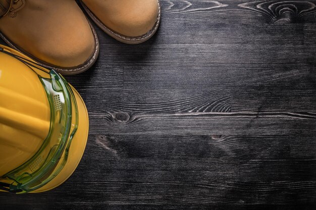 Composition of goggles building helmet safety boots on wooden board