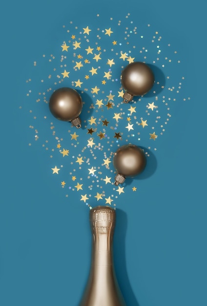 Foto composizione di bottiglia d'oro di champagne e decorazione natalizia su sfondo blu