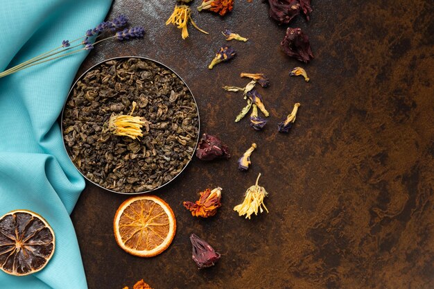 Photo composition of green flower tea and dried orange slices on blue and brown backgrounds top view largeleaf tea dried flowers and citrus chips on contrasting backgrounds