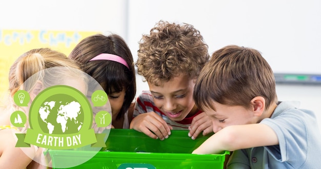 Foto composizione del logo del globo verde e del testo della giornata della terra sui bambini che guardano nella scatola di riciclaggio