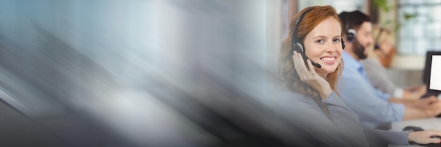 Composition of happy caucasian businesswoman wearing phone headset in office with motion blur