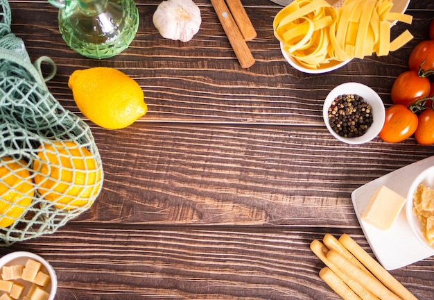 Composition of healthy food ingredients for cooking italian pasta Spaghetti parmesan basil lemon on wooden kitchen rustic table Top view Copy space