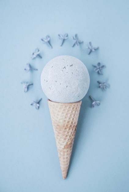 Composition of ice cream cone with bath ball. Flat Lay. Top View. Lilac flowers