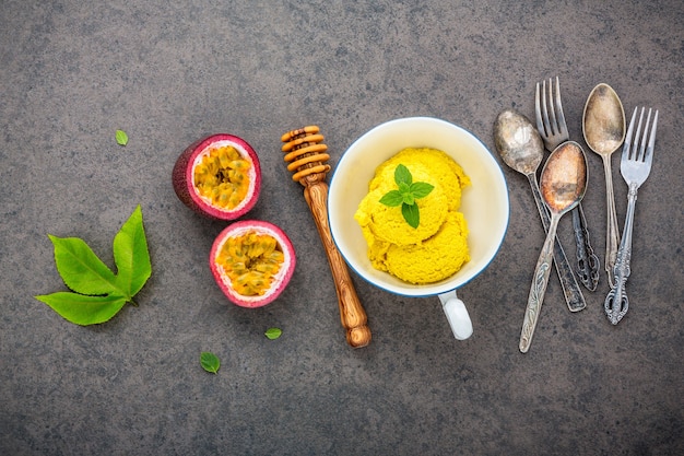 Composition of ice cream passion fruit flavor in vintage bowl setup on dark stone 