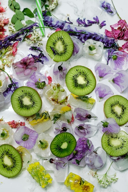 Composition of Kiwi slices with flowers and ice on white background