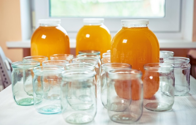 Composition of a large number of jars and three jars of honey standing on a white table against a background of light