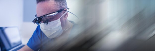 Composition of male dentist in face mask and protective glasses\
with blurred light trails