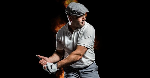 Composition of male golf player over flames on black background