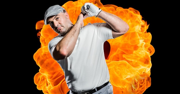 Composition of male golf player over flames on black background