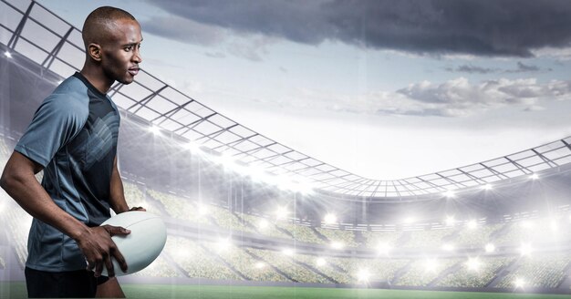 Composition of male rugby player holding rugby ball over sports stadium