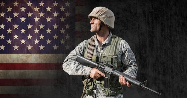 Photo composition of male soldier holding gun,looking away, against american flag on black