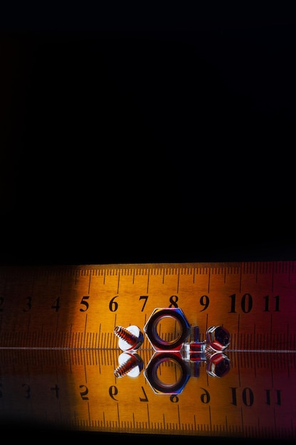 Composition of metal chromeplated nuts of different sizes and a metal ruler Black background