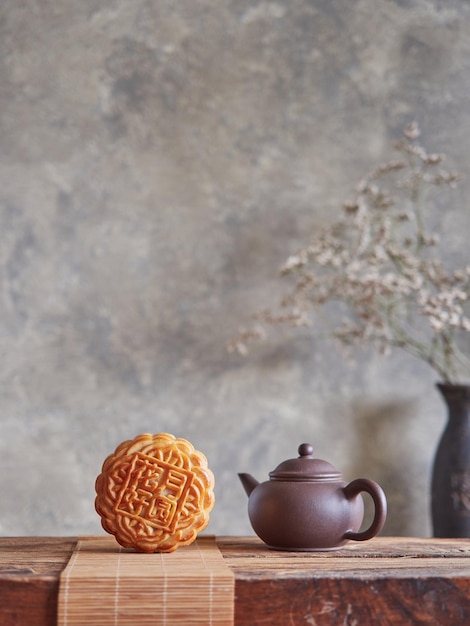 Composition of the MidAutumn festival Front view of moon cake on bamboo mat next to small brown teapot on wooden table