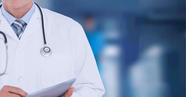 Composition of midsection of male doctor in lab coat using tablet over out of focus hospital