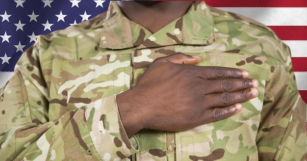 Composition of midsection of male soldier with hand on heart, against american flag