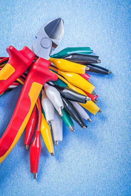 Composition of multicolored cable crocodiles nippers on blue background.