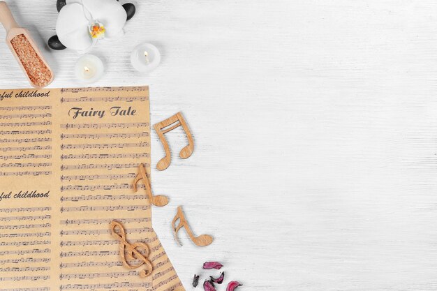 Photo composition of music sheets and spa supplies on wooden background