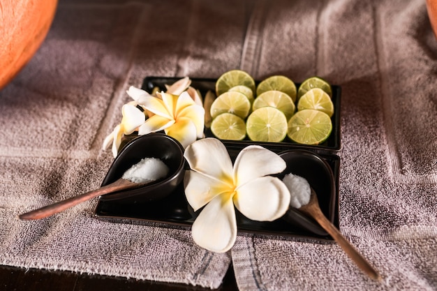 Composition of nature spa ingredients in wooden tray: lime, natural scrubs, flowers