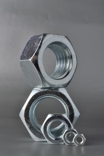 composition of new bolts and nuts of different sizes on a gray background.