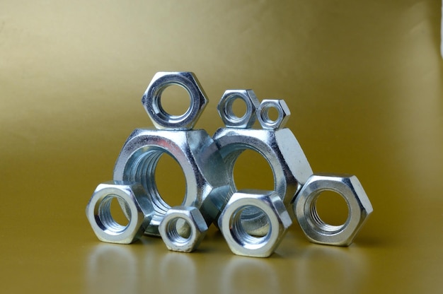 Composition of new nuts and bolts of different sizes on a yellow background