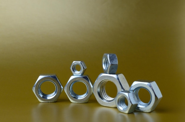 Composition of new nuts and bolts of different sizes on a yellow background