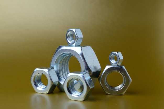 Composition of new nuts and bolts of different sizes on a yellow background