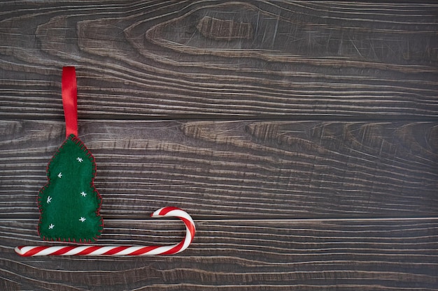 Foto composizione di un albero di capodanno e caramelle di natale. slitta su uno sfondo di legno scuro.