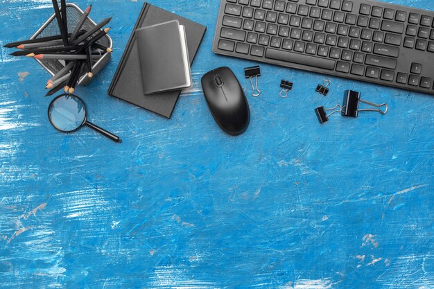 Composition of office supplies and equipment in black and blue background, top view 