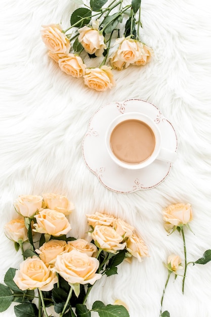 Composition of pastel tea rose bouquet flowers and a cup of cocoa on white background floral