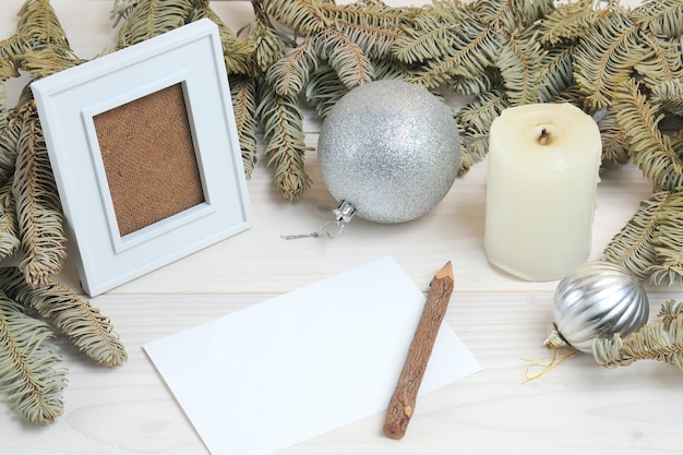 Composition of a photo frame, paper, pencil on a Christmas theme on a white wooden surface