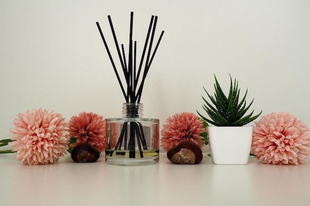 Composition of pink artificial flowers incense sticks in a glass vase with essential oil still life