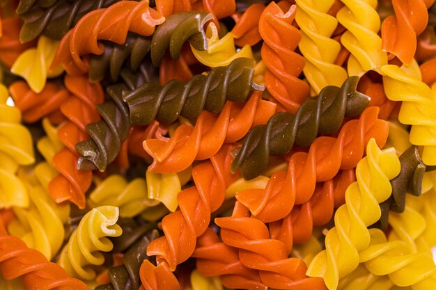 Composition of raw pasta uncooked tricolore fusilli pasta twist shape close up and selective focus on colorful fusilli pasta