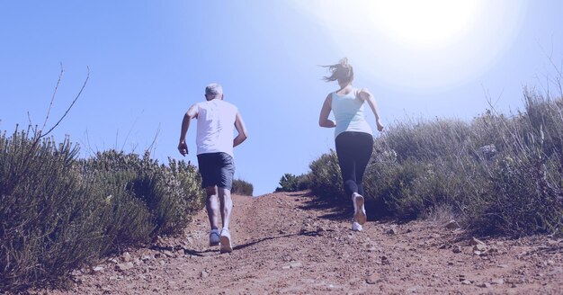 Composition of rear view of man and woman running in countryside