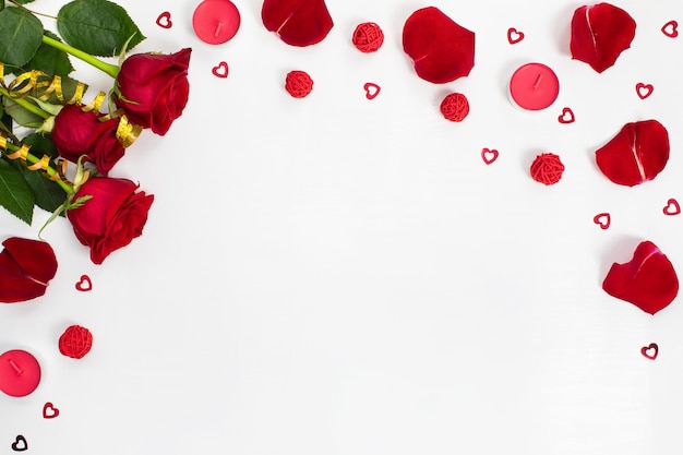 Composition of red roses rose petals sequin hearts candles gold ribbons on white background Content for Birthday Valentines Day Womens day Mothers day Flat lay top view close up copy space