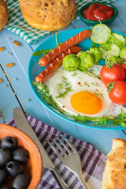 композиция из деревенских яиц для завтрака и колбасы с овощами на деревянном фоне