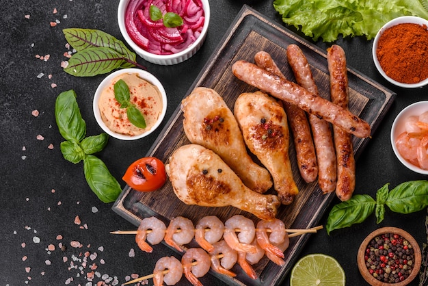 Composition of sausages, chicken, pork and shrimp prepared on grill, as well as vegetables prepared on grill with spices and herbs. Cooking on fire