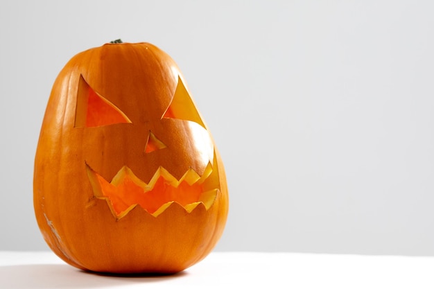 Composition of scary halloween carved orange pumpkin on white background. halloween tradition and celebration concept.