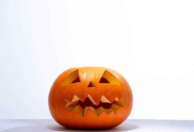 Composition of scary halloween carved orange pumpkin on white background. halloween tradition and celebration concept.