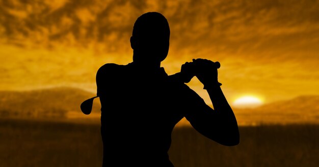 Composition of silhouette of male golf player over landscape
and sun setting with copy space