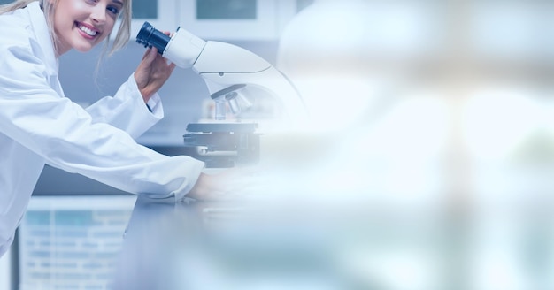 Photo composition of smiling female lab technician using microscope, with blurred copy space to right
