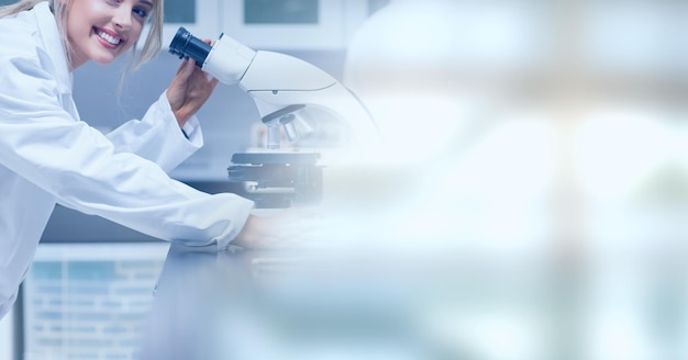 Composition of smiling female lab technician using microscope, with blurred copy space to right