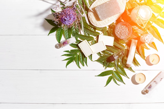 Composition of spa treatment on white wooden table with space for text top view sun flare