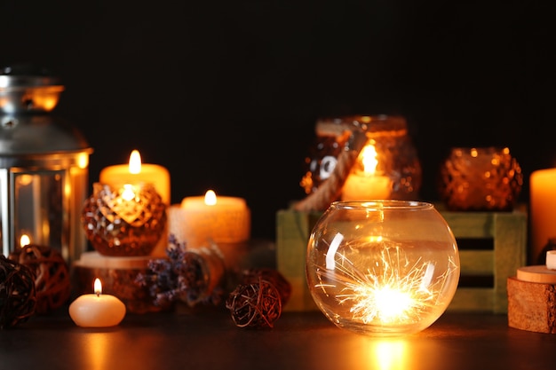 Composition of sparkler, glass vase and decor on dark background