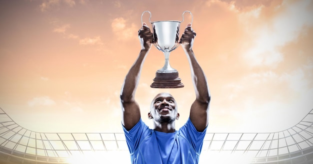 Composition of sportsman celebrating victory, holding trophy at stadium