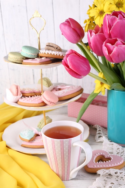 Composition of spring flowers tea and cookies on table closeup