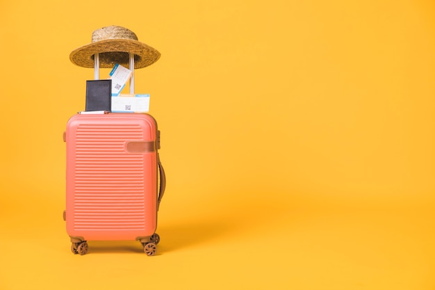 Composition of suitcase and tickets passport and hat on it